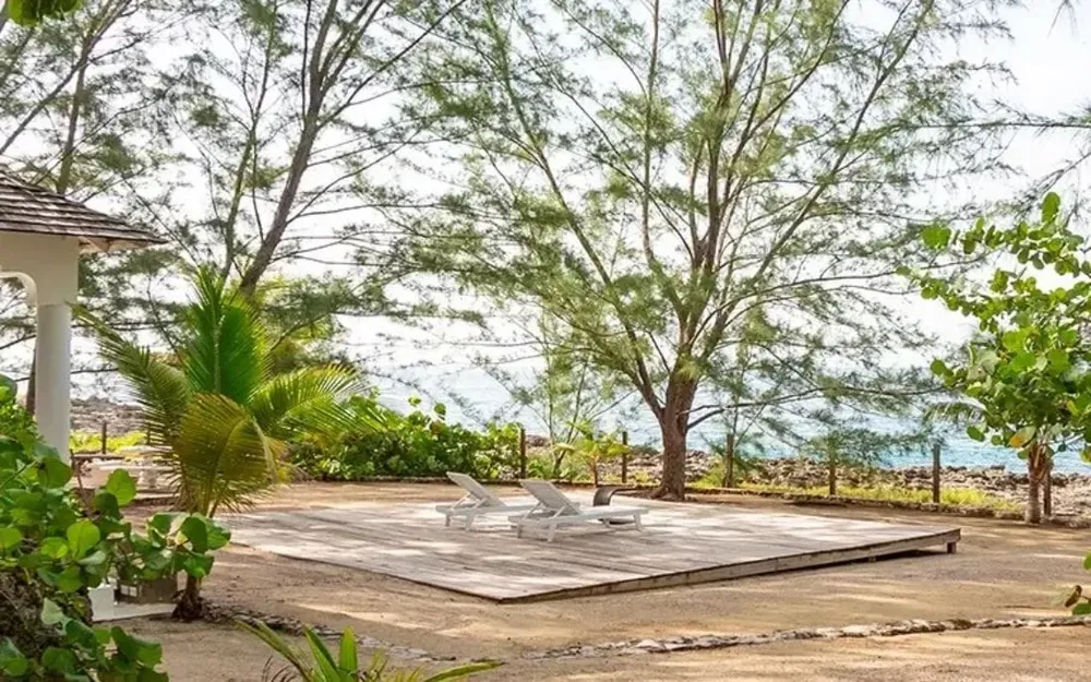 Wooden oceanfront deck with lounge chairs surrounded by nature