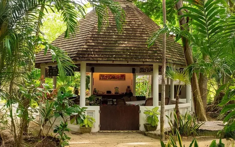 Open-air lounge area in a tropical setting, used for dining and gatherings